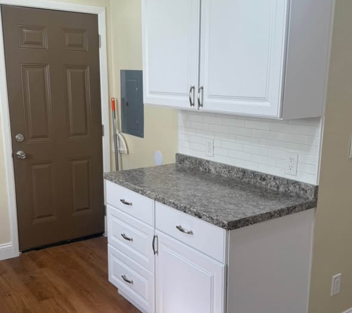 Kitchen with white cabinets, countertop, and entry door at 2103 N C St