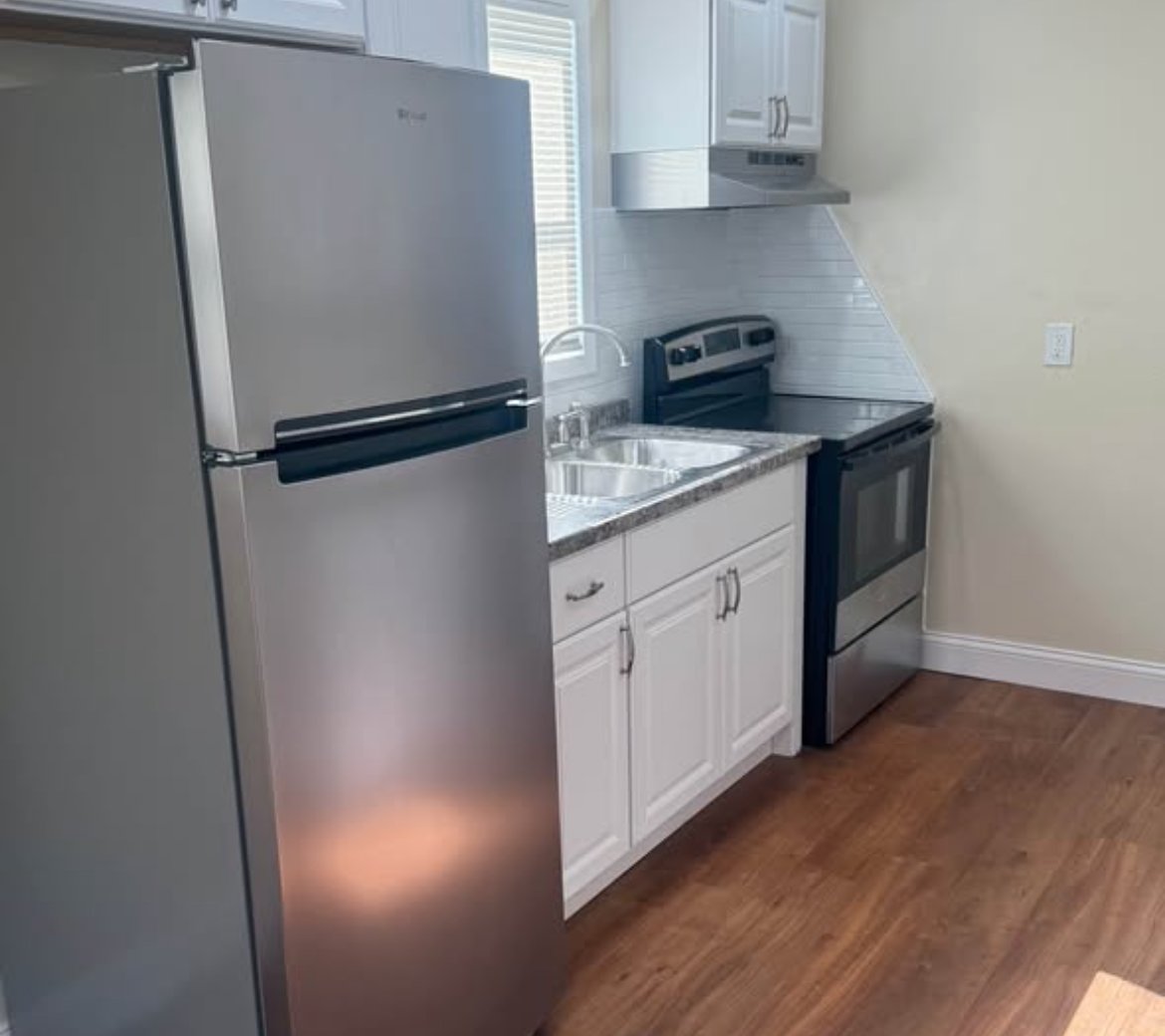 Remodeled kitchen with stainless refrigerator, white cabinets, and wood-look floors at 2103 N C St
