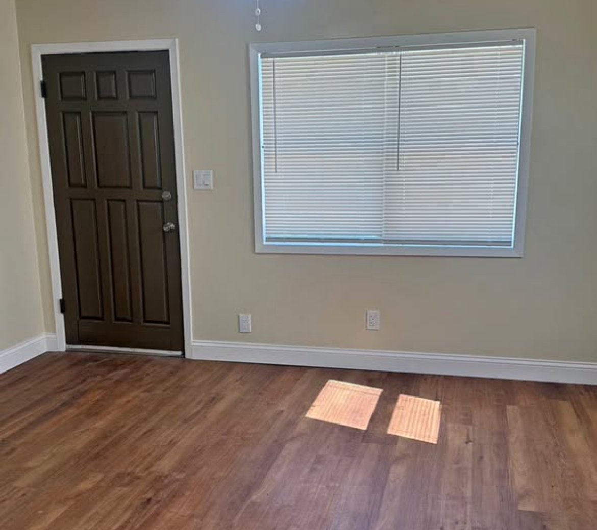 Living area with wood-look floors, front door, and window blinds at 2103 N C St