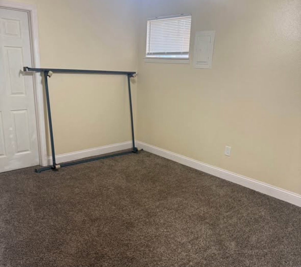 Bedroom with brown carpet, window blinds, and bed frame at 1702 W Olive St