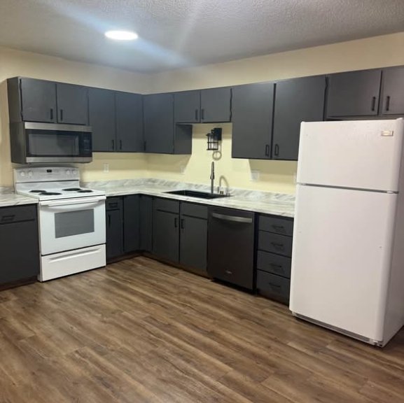 Updated kitchen with dark cabinets, white appliances, and wood-look floors at 1702 W Olive St