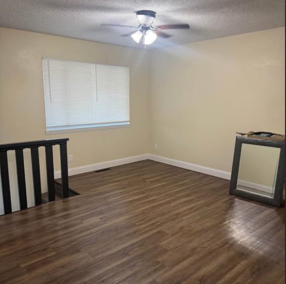 Living area with wood-look floors, ceiling fan, and stair railing at 1702 W Olive St
