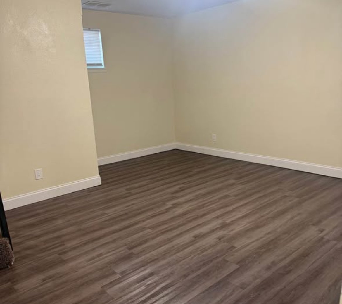 Empty room with wood-look flooring and high window at 1702 W Olive St